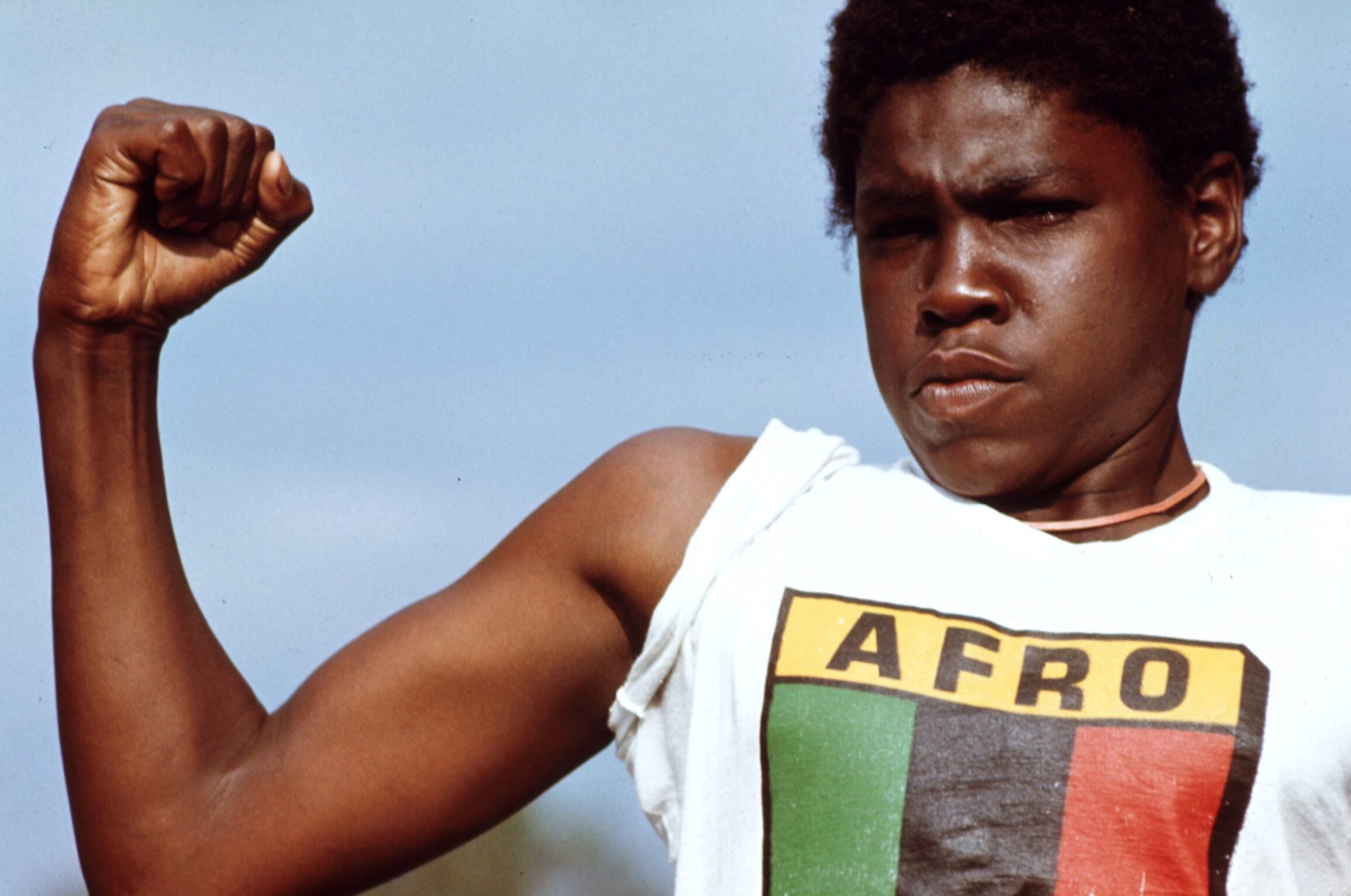 A young man in an AFRO T-shirt raises his fist, Chicago, 1970s